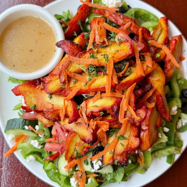 Tandoori chicken salad with mixed greens, vegetables, cheese, and a side of dressing.
