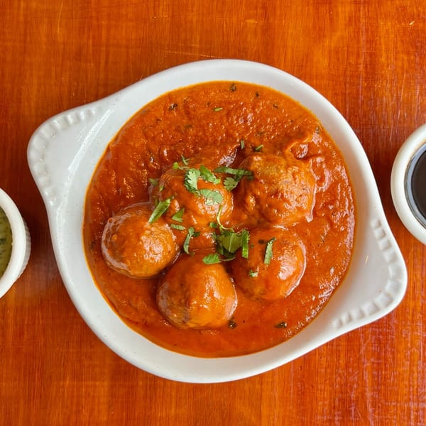 Indian Malai Kofta, vegetable and paneer dumplings in a rich, creamy tomato sauce, garnished with cilantro.