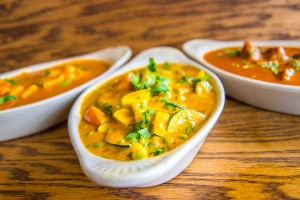 Three dishes of curry with fresh spices.