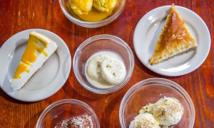A table full of six appetizing Indian & Mediterranean deserts.