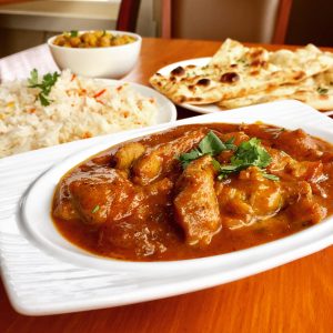 A plate of Mango Curry, fresh naan bread, rice, and humus.