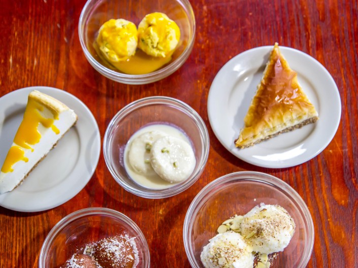 A table full of six appetizing Indian & Mediterranean deserts.