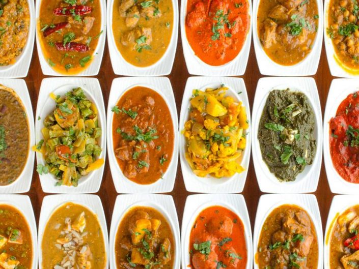 Multiple plates in a row with a variety of Indian and Mediterranean foods.